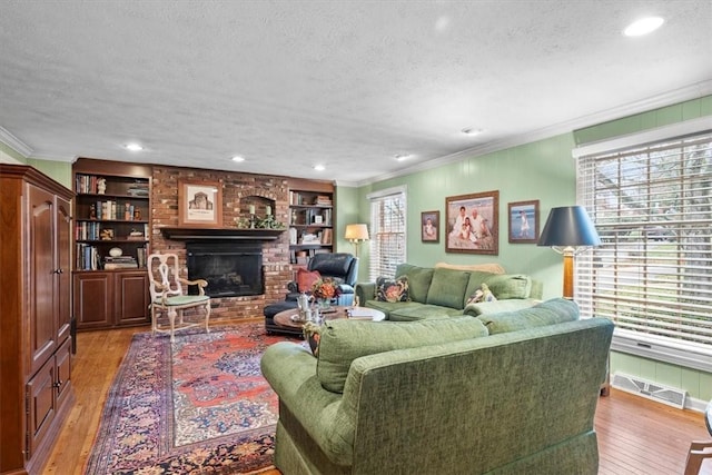 living room featuring wood-type flooring, a fireplace, a textured ceiling, and built in shelves