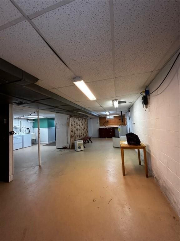 basement featuring a paneled ceiling and washing machine and clothes dryer