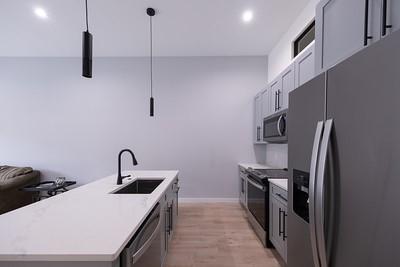 kitchen featuring sink, appliances with stainless steel finishes, a kitchen island with sink, gray cabinetry, and decorative light fixtures