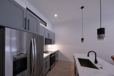 kitchen featuring pendant lighting, sink, appliances with stainless steel finishes, gray cabinetry, and light stone counters