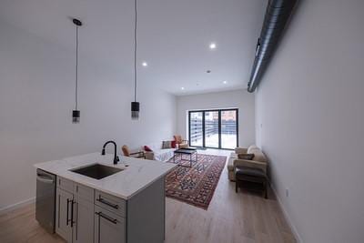 kitchen featuring gray cabinets, pendant lighting, dishwasher, an island with sink, and sink