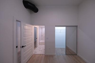 unfurnished bedroom featuring a towering ceiling and light hardwood / wood-style floors