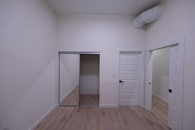 unfurnished bedroom featuring multiple closets and light wood-type flooring