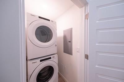 laundry room featuring electric panel and stacked washer / dryer