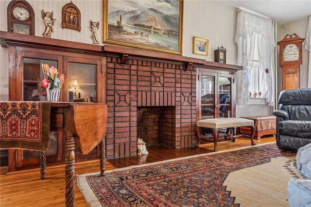 sitting room with hardwood / wood-style flooring and a brick fireplace