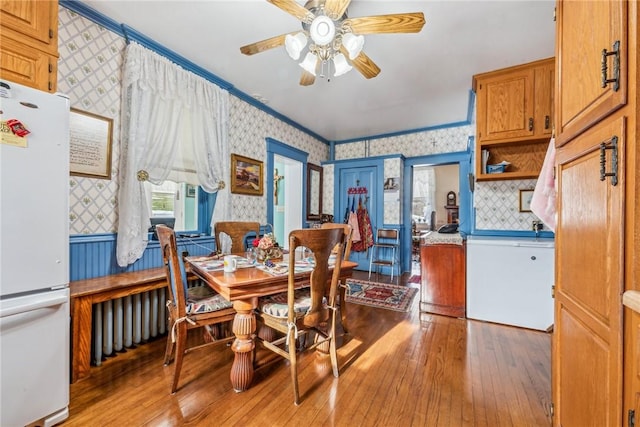 dining space with crown molding, ceiling fan, and light hardwood / wood-style floors