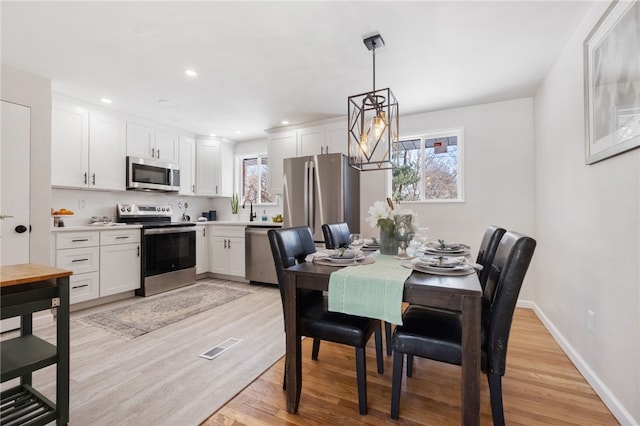 dining space with sink, a chandelier, and light hardwood / wood-style flooring