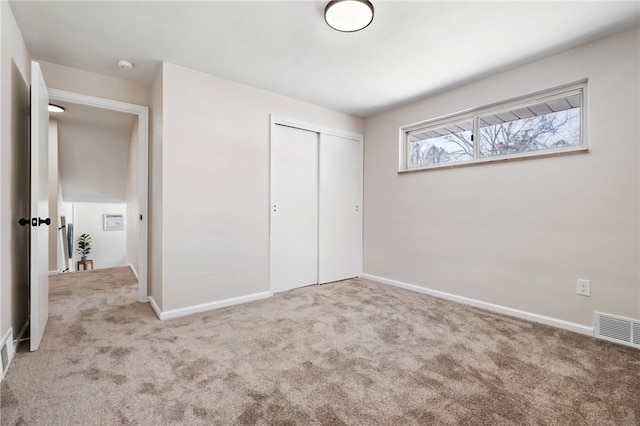 unfurnished bedroom with light carpet and a closet