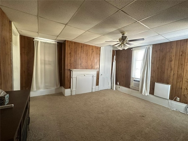 interior space with ceiling fan, carpet floors, and wooden walls