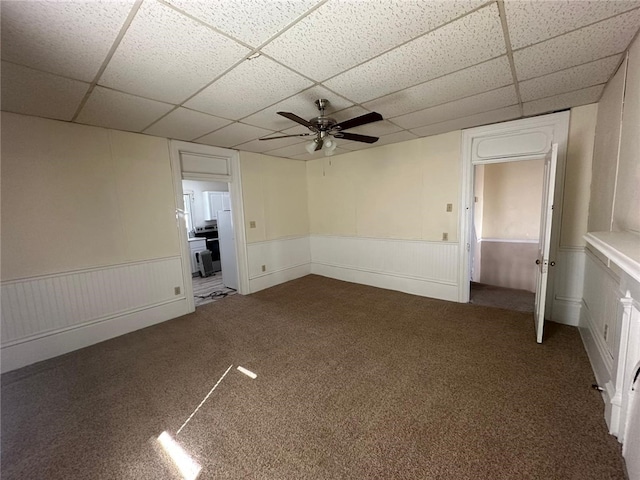 spare room featuring a drop ceiling, ceiling fan, and carpet