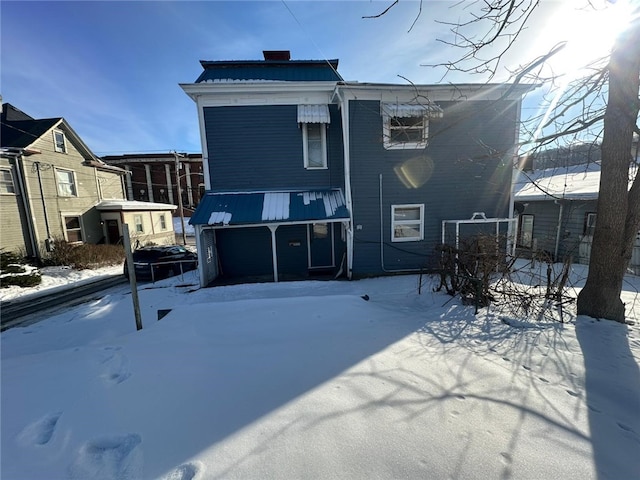 snow covered back of property featuring a garage