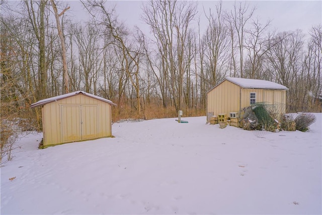 snowy yard featuring a storage unit