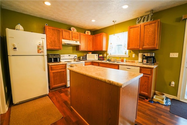 kitchen featuring sink, a center island, hanging light fixtures, dark hardwood / wood-style flooring, and white appliances