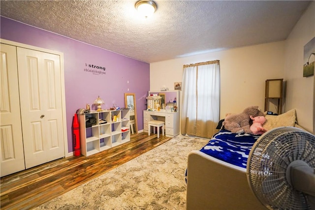 bedroom with a textured ceiling, dark hardwood / wood-style flooring, and a closet