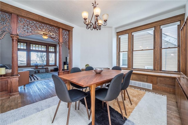 dining room featuring an inviting chandelier, decorative columns, and hardwood / wood-style floors