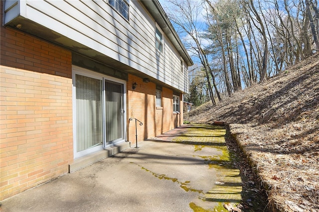 view of side of property with brick siding and a patio