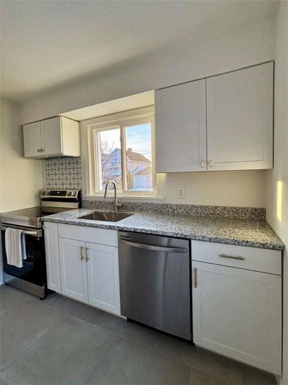 kitchen with tile patterned floors, sink, stainless steel appliances, light stone countertops, and white cabinets