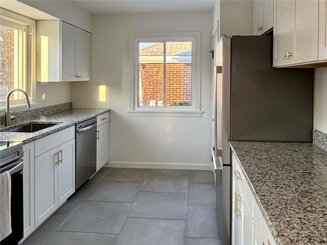 kitchen featuring sink, light stone countertops, white cabinets, and appliances with stainless steel finishes