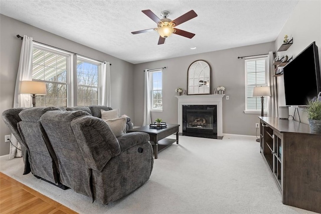 carpeted living room with ceiling fan, plenty of natural light, and a textured ceiling