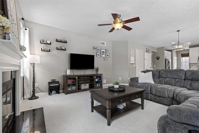 carpeted living room featuring ceiling fan with notable chandelier and a textured ceiling