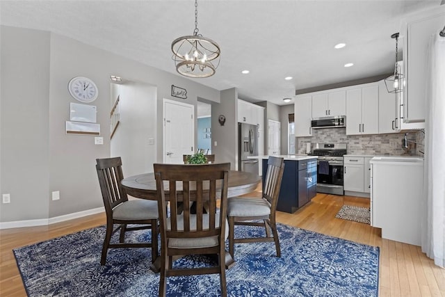 dining space with sink, an inviting chandelier, and light wood-type flooring