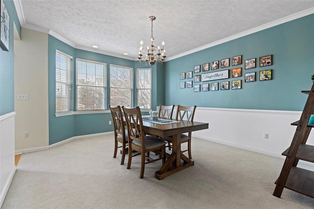 carpeted dining space featuring crown molding, a textured ceiling, and an inviting chandelier