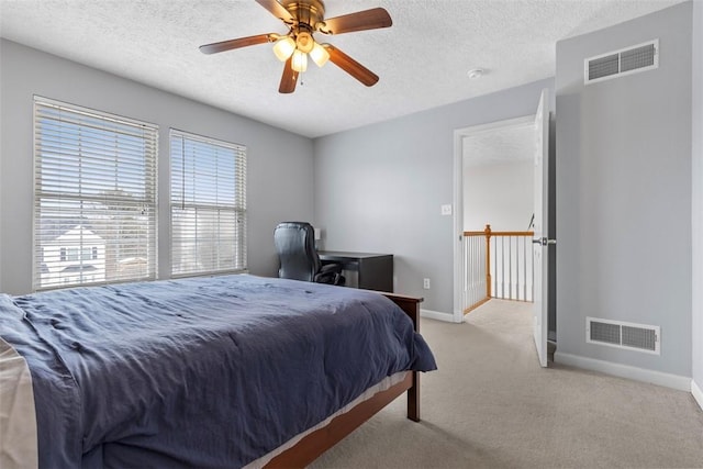 bedroom featuring light colored carpet, a textured ceiling, and ceiling fan