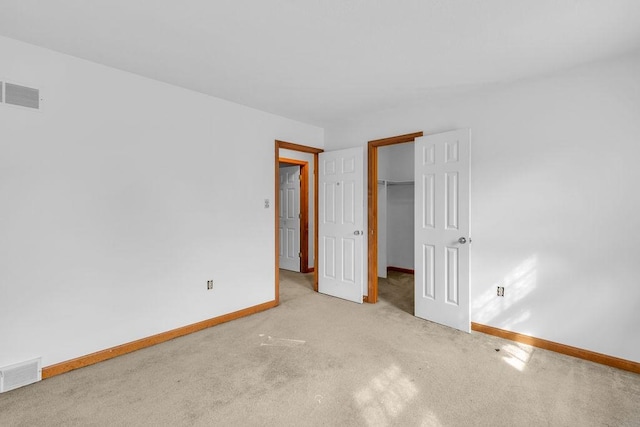 unfurnished bedroom with light colored carpet, a closet, and a walk in closet