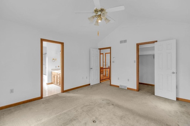 unfurnished bedroom featuring ensuite bathroom, a walk in closet, light colored carpet, ceiling fan, and a closet