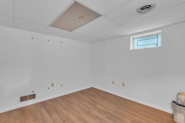 basement featuring a paneled ceiling and light wood-type flooring