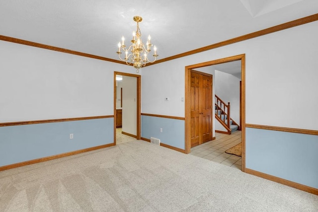 carpeted spare room with ornamental molding and a notable chandelier