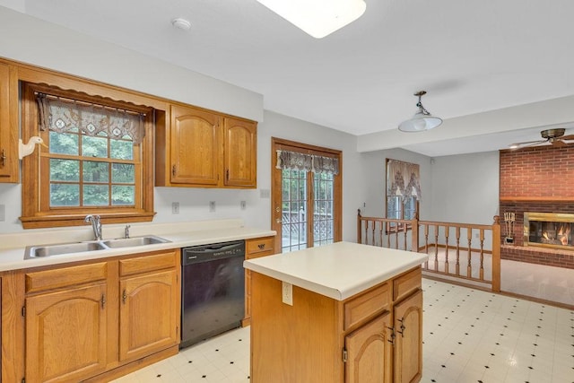 kitchen featuring sink, a brick fireplace, dishwasher, and a kitchen island