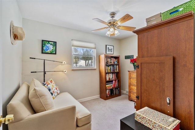 living area with light carpet and ceiling fan