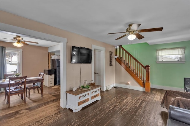 living room featuring dark wood-type flooring and ceiling fan