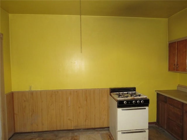 kitchen featuring wooden walls and white range with gas cooktop