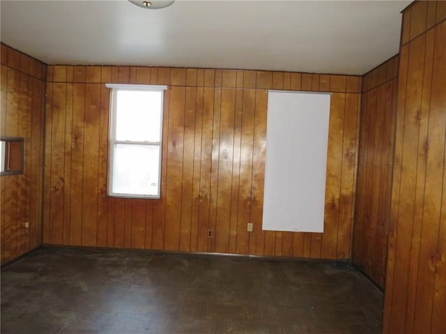 empty room with dark parquet flooring and wood walls