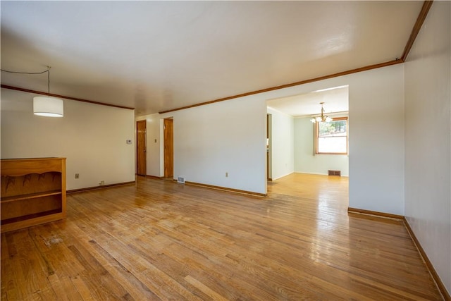 spare room with an inviting chandelier, crown molding, and light hardwood / wood-style floors