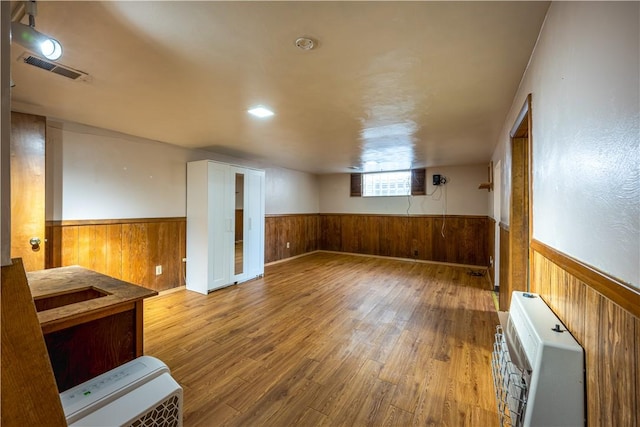 unfurnished room with heating unit and wood-type flooring