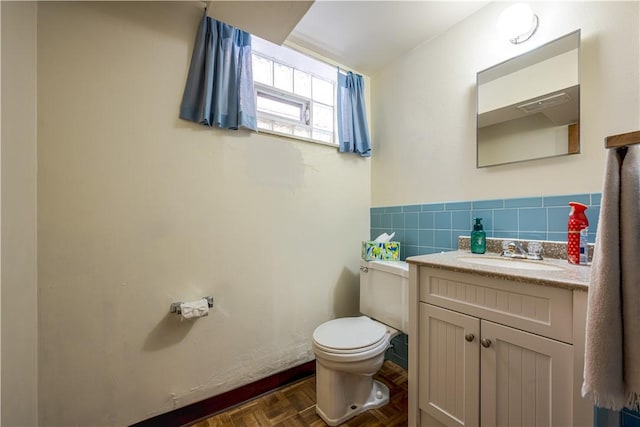 bathroom featuring parquet floors, vanity, toilet, and tile walls