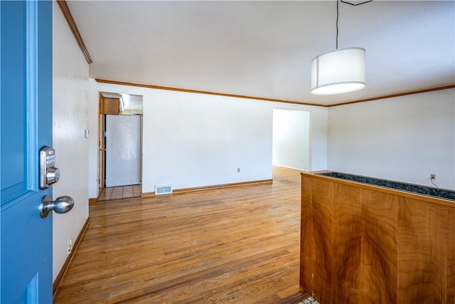 unfurnished room featuring crown molding and light wood-type flooring