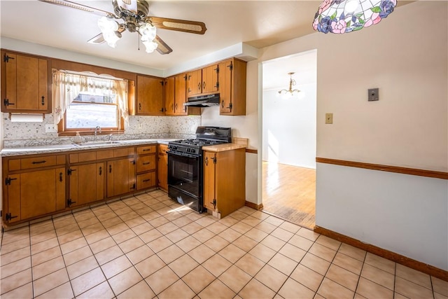 kitchen featuring black range with gas cooktop, sink, tasteful backsplash, light tile patterned floors, and ceiling fan with notable chandelier