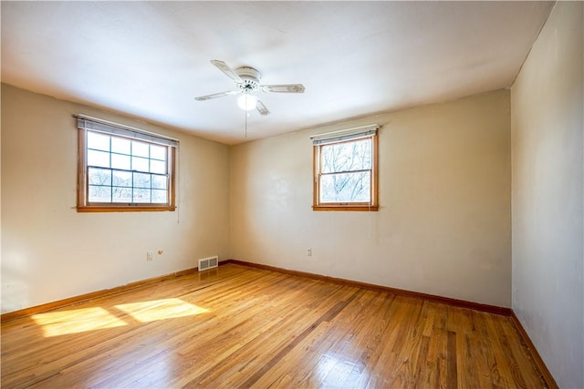 unfurnished room featuring hardwood / wood-style flooring, ceiling fan, and a wealth of natural light