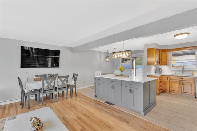 kitchen with gray cabinets, a kitchen island, sink, and light hardwood / wood-style floors