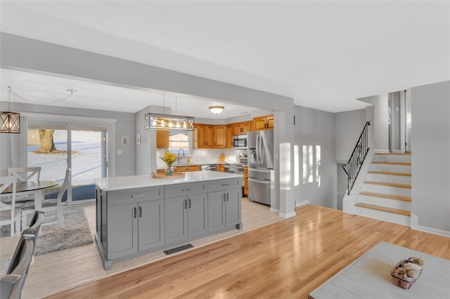 kitchen featuring gray cabinets, appliances with stainless steel finishes, a center island, and pendant lighting