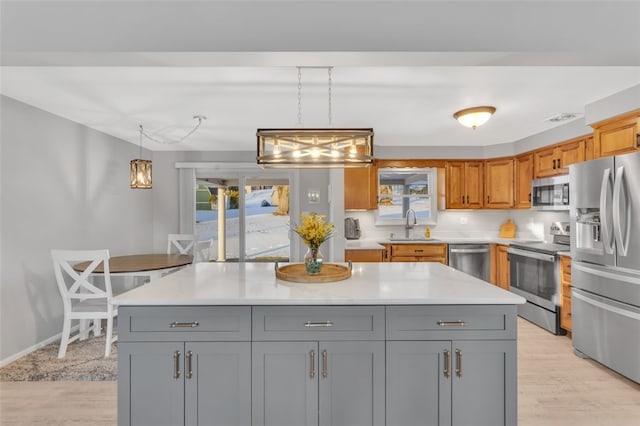 kitchen with pendant lighting, appliances with stainless steel finishes, sink, and gray cabinetry