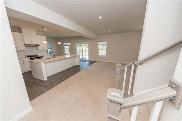 kitchen with white cabinetry, hanging light fixtures, a kitchen breakfast bar, and an island with sink