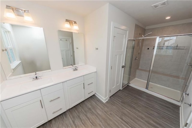 bathroom featuring wood-type flooring, a shower with door, and vanity