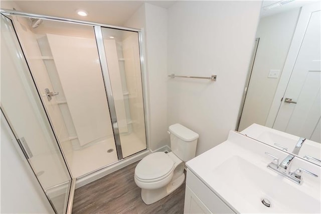 bathroom with vanity, hardwood / wood-style flooring, a shower with shower door, and toilet