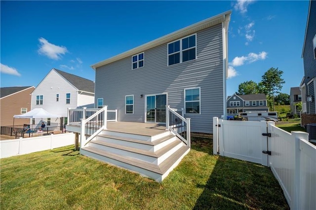 rear view of house featuring a yard and a deck