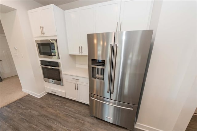 kitchen with appliances with stainless steel finishes, dark hardwood / wood-style flooring, and white cabinets